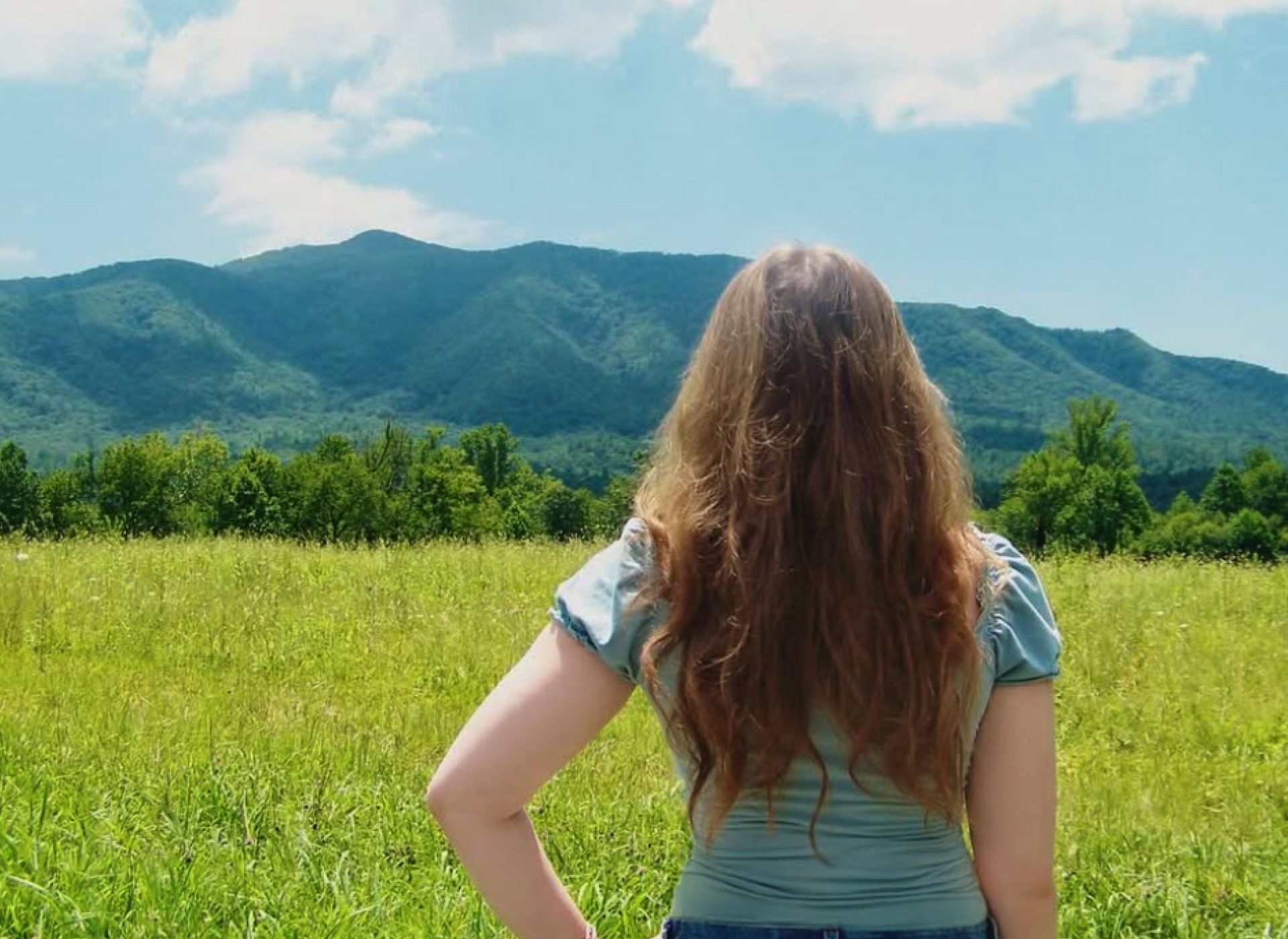 teen girl with long hair looks out at mountain landscape