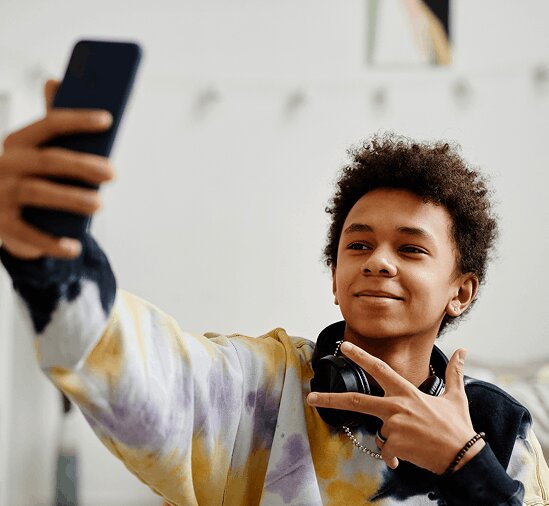 Young boy looking at phone with headphones around neck